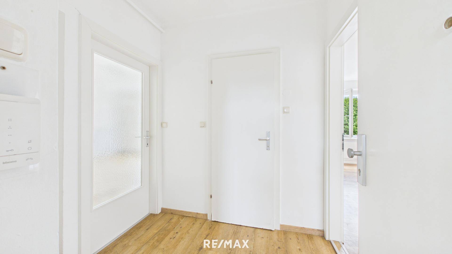 Eingangsbereich mit Laminatboden und mehreren Türen, bietet Zugang zu den angrenzenden Zimmern.