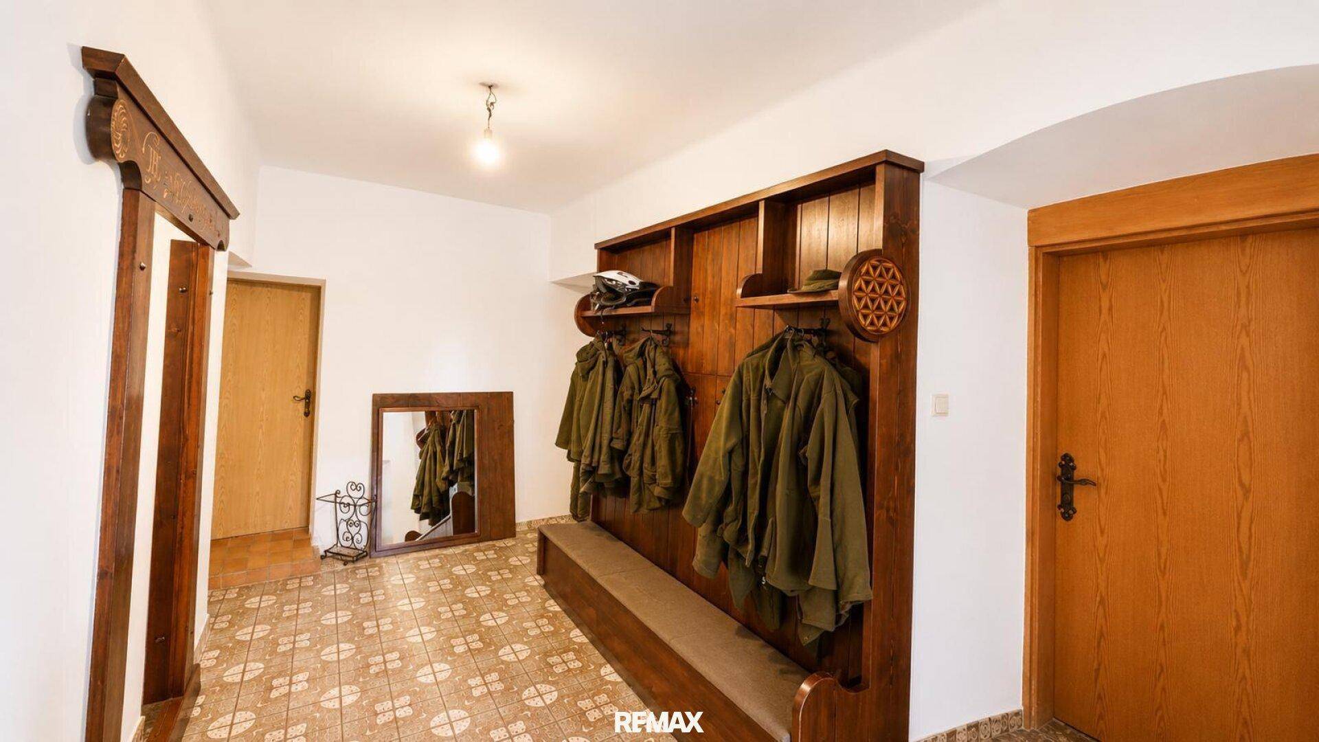 Eingangsbereich mit gemusterten Bodenfliesen, traditioneller Holzgarderobe und Holztüren.