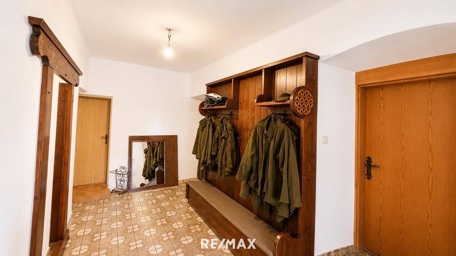 Eingangsbereich mit traditioneller Holzgarderobe, Spiegel und gemustertem Fliesenboden.
