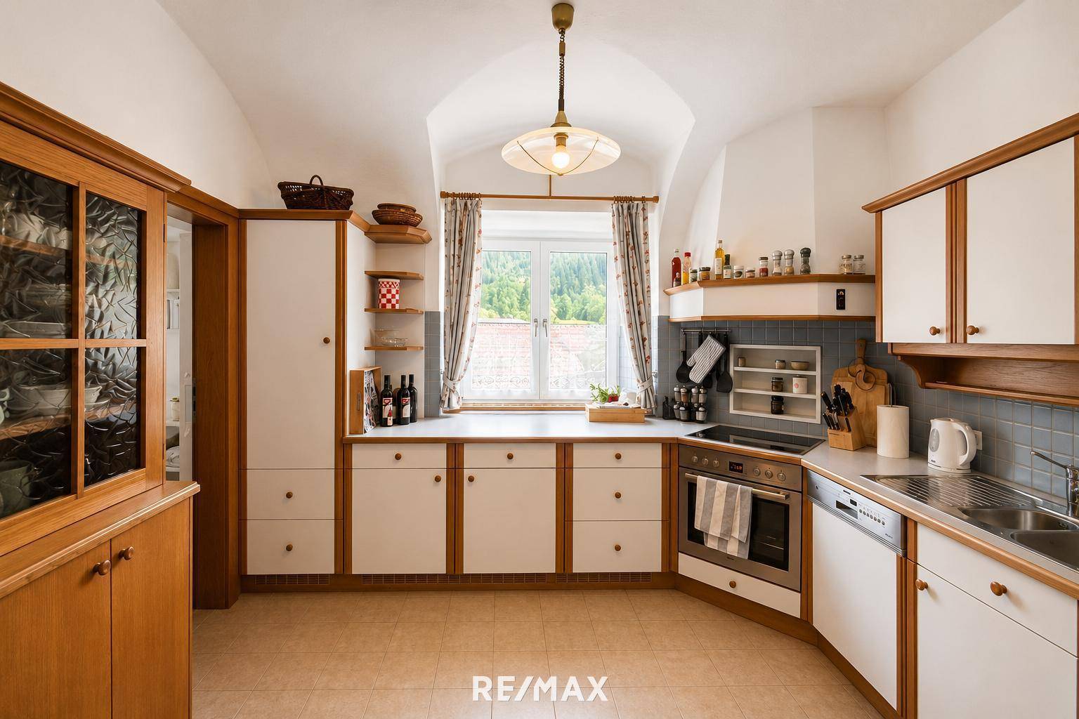 Traditionelle Küche mit gewölbter Decke, weißen Schränken und Holzdetails, hell durch Fenster.
