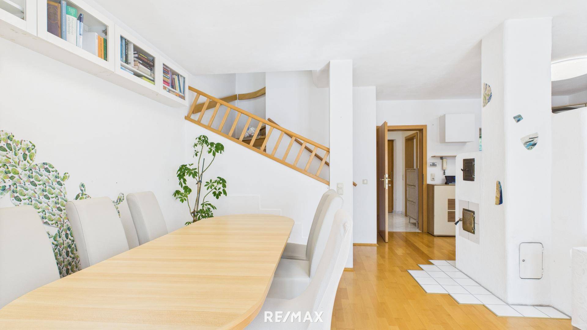 Heller Essbereich mit Holztisch, Stühlen und Zugang zur oberen Etage über eine Holztreppe.