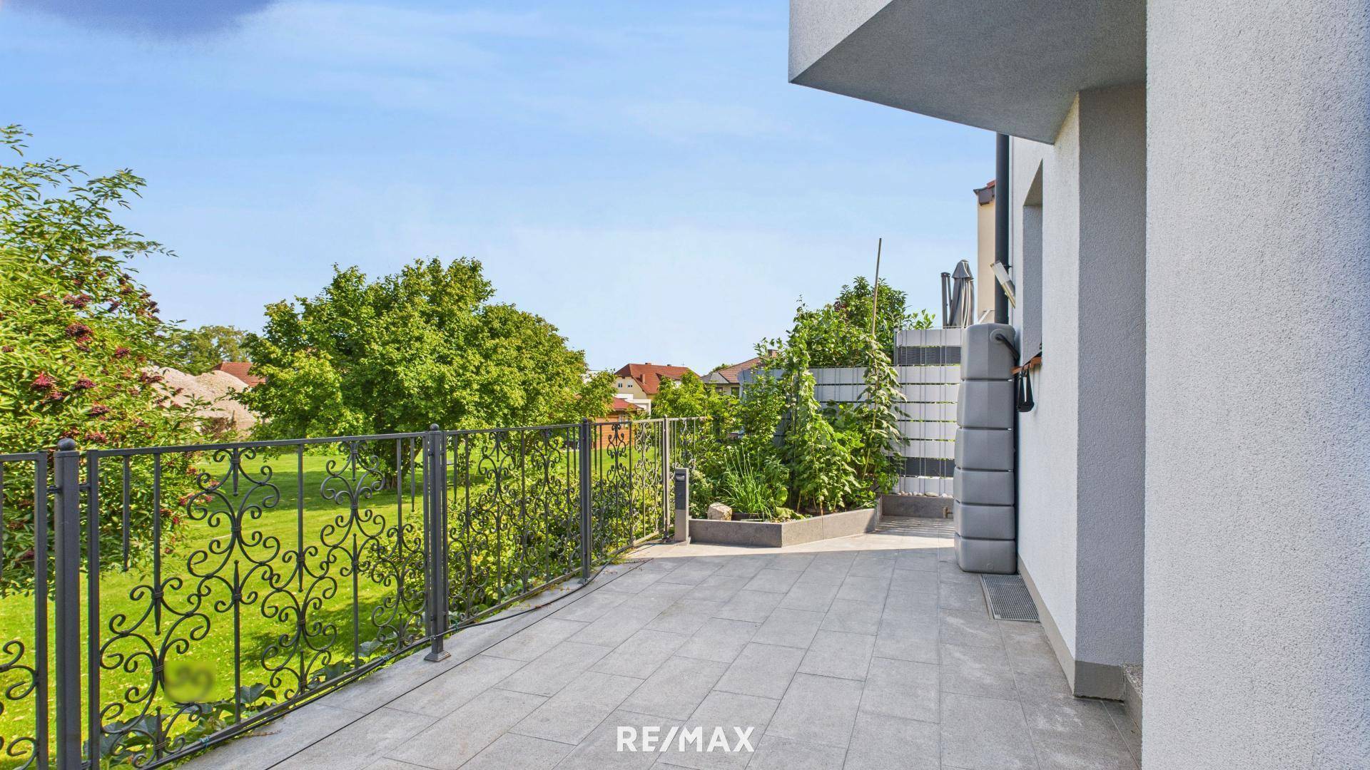 Gepflasterte Terrasse mit schmiedeeisernem Geländer und weitem Blick ins Grüne.
