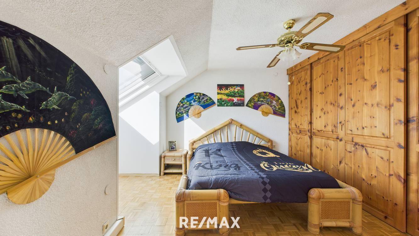 Schlafzimmer mit Holzbett, Einbauschrank und Dachfenster, das viel natürliches Licht hereinlässt.