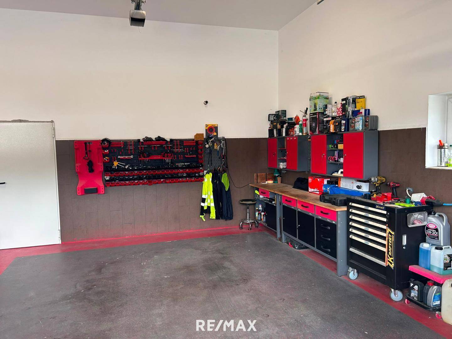 Detailansicht des Werkstattbereichs in der Garage mit roten Schränken, Werkzeugen und einer Werkbank.
