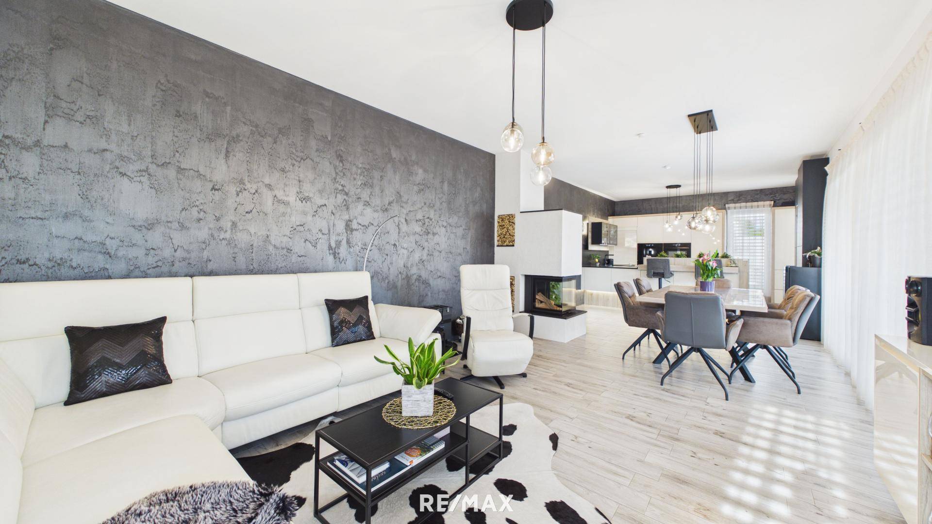 Offener Wohn- und Essbereich mit weißem Sofa, Kamin und modernem Design.