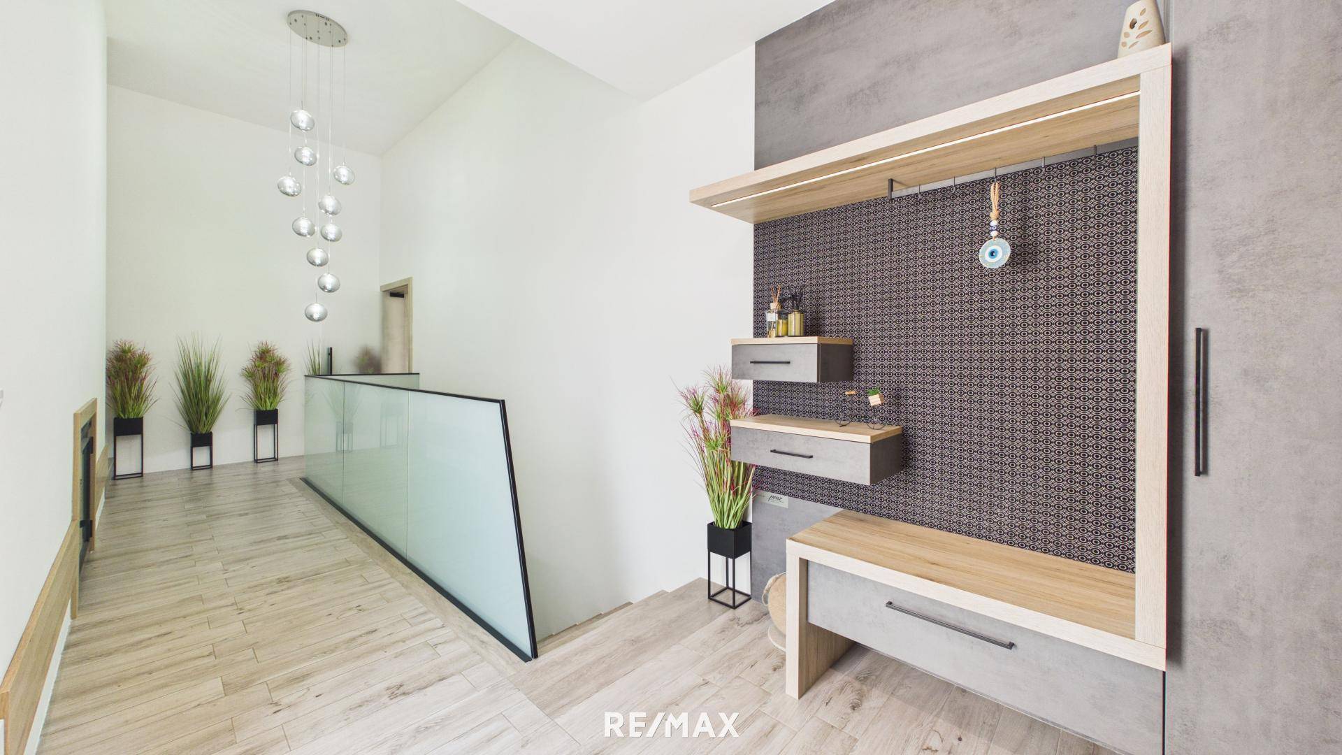Heller Flur mit modernem Garderobenbereich, Holzfußboden und einer eleganten Hängelampe.