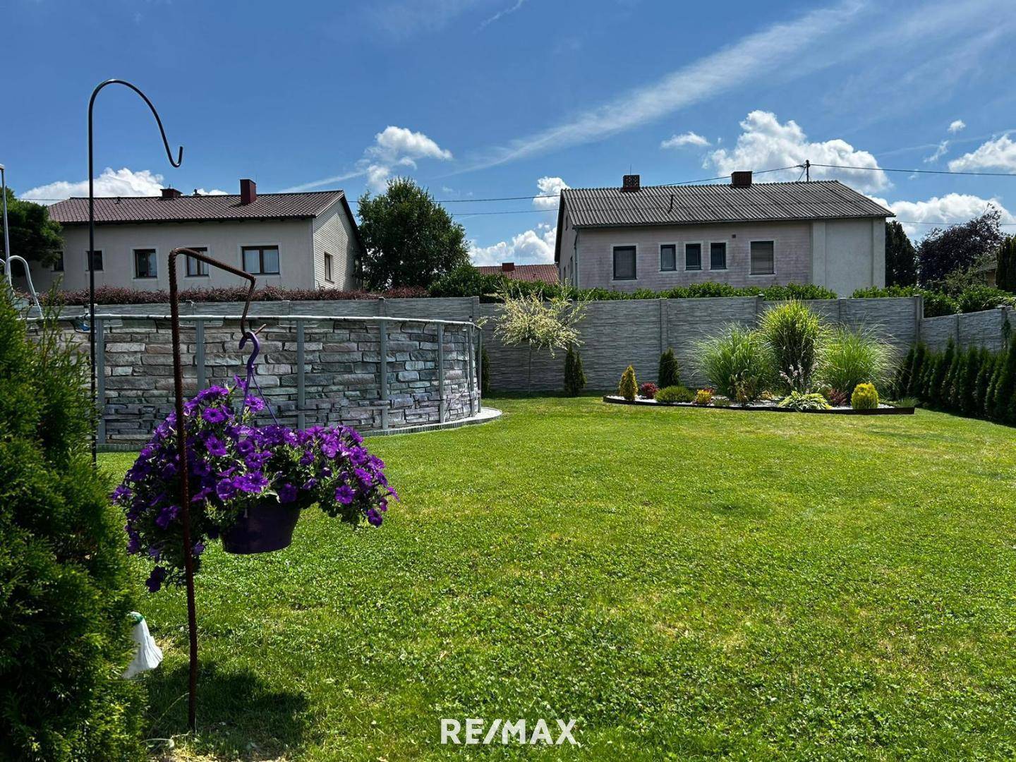 Weitläufiger Garten mit Rasenfläche, einem oberirdischen Pool und dekorativen Pflanzen.