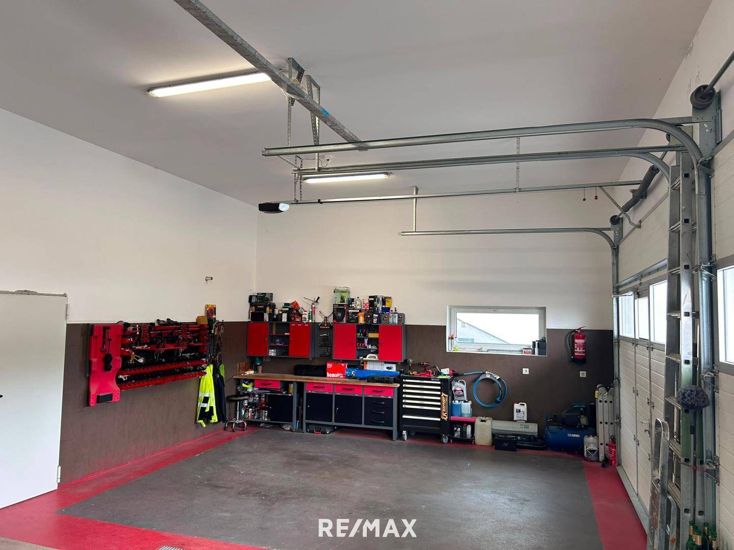 Große Garage mit umfangreicher Werkstattausstattung, roten Schränken und Werkzeugen an der Wand.