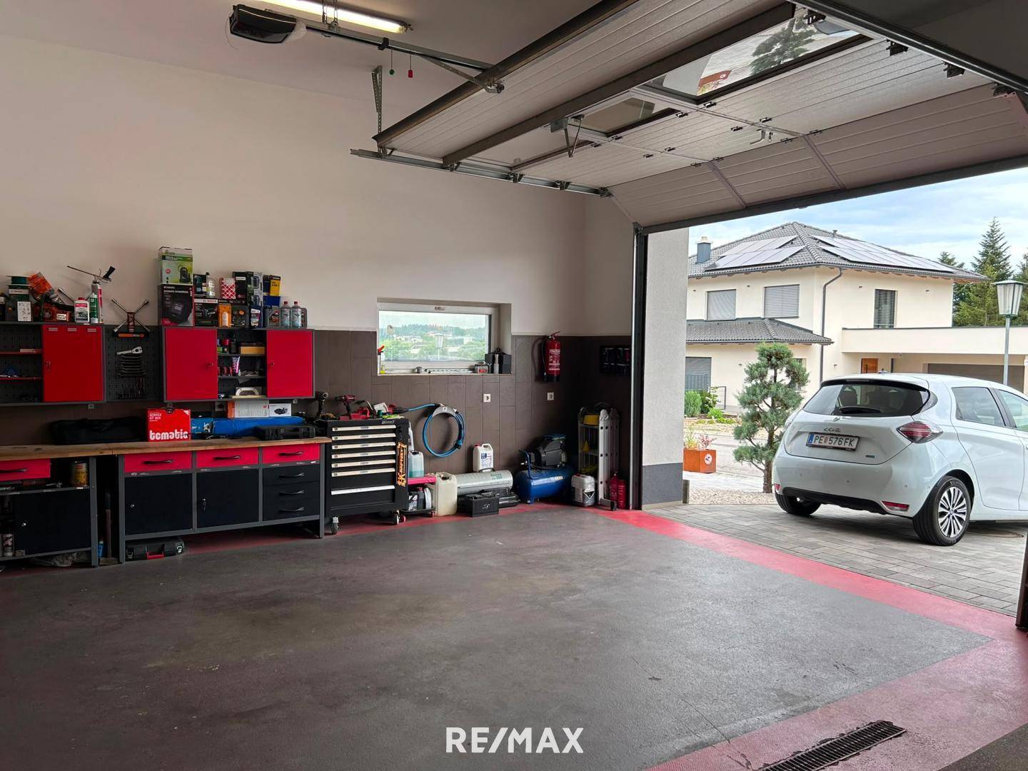 Weit geöffnete Garage mit einem Auto davor und einem Blick auf die umliegende Wohnbebauung.