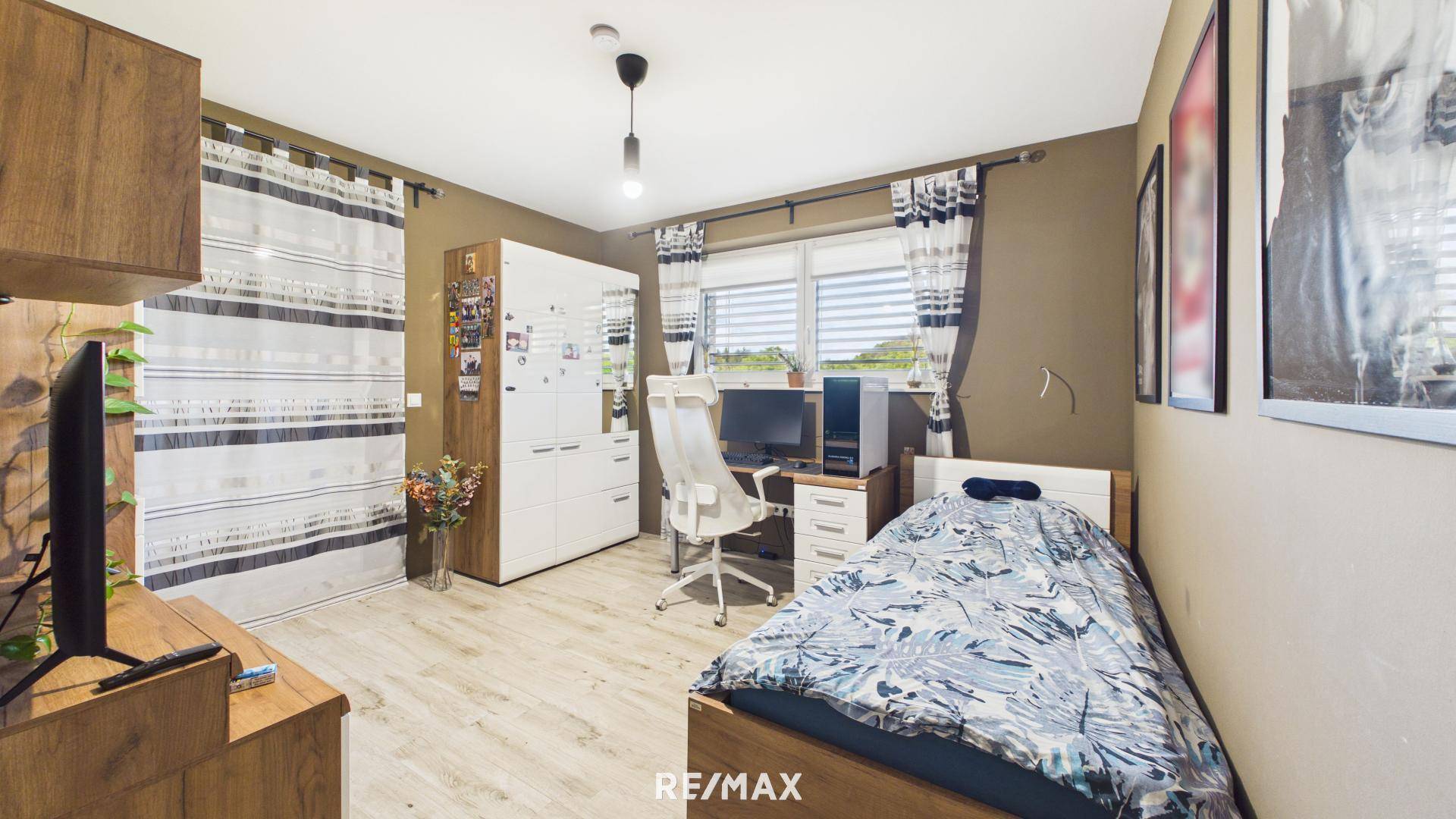 Gemütliches Schlafzimmer mit Einzelbett, Schreibtisch und Holzmöbeln.