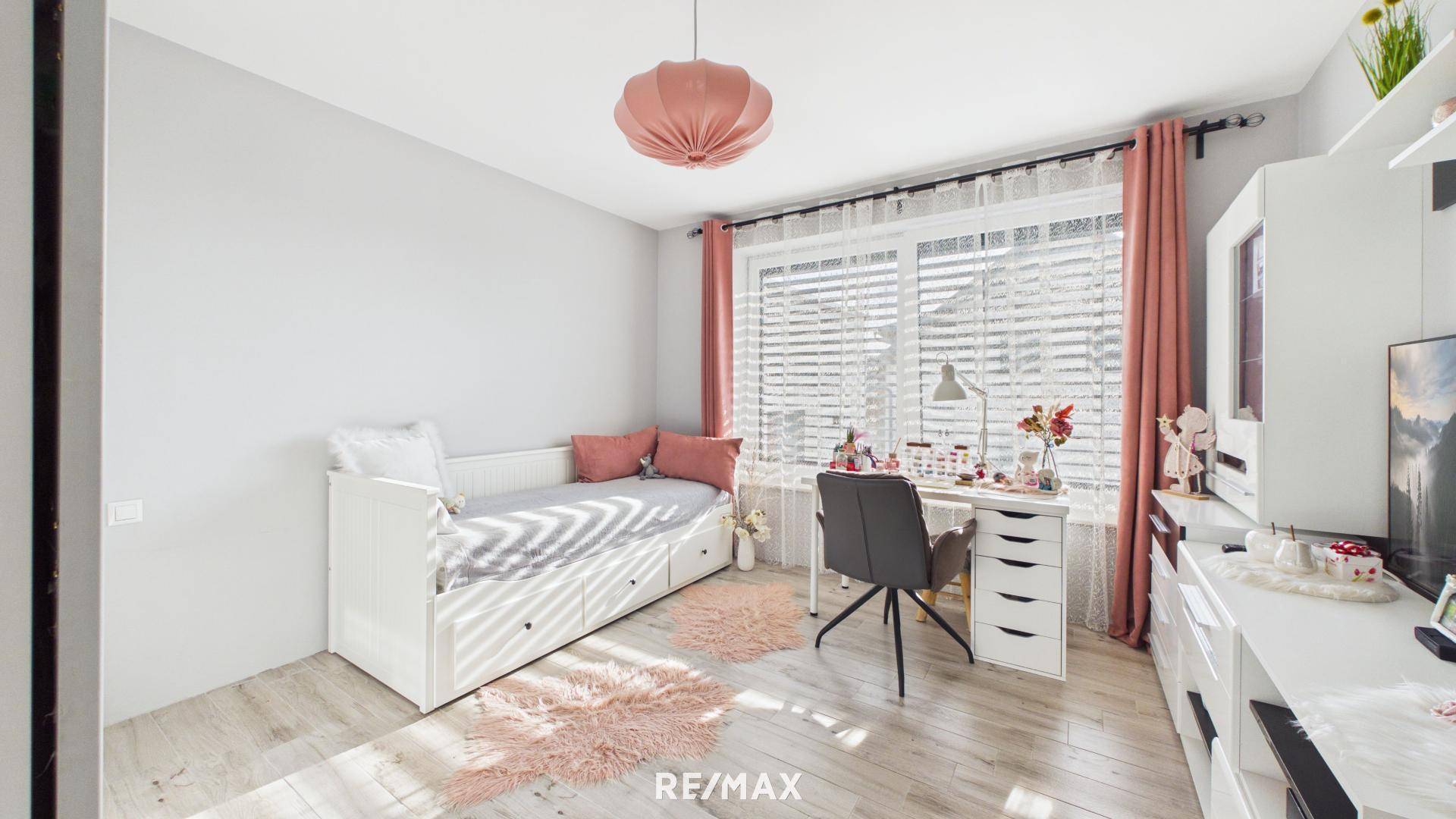 Helles Kinderzimmer mit Einzelbett, Schreibtisch und rosa Dekoration.