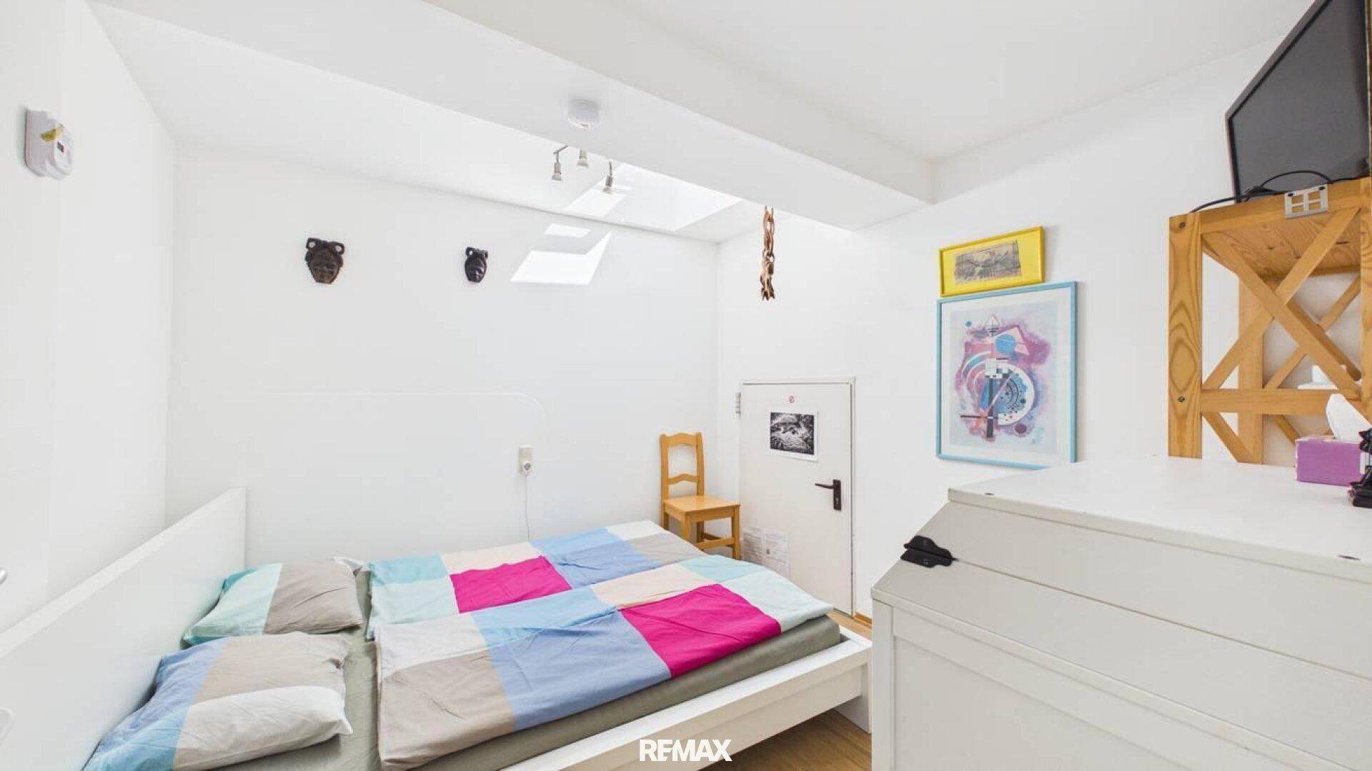 Gemütliches Schlafzimmer mit Doppelbett, Holzboden und Dachfenster für natürliches Licht.