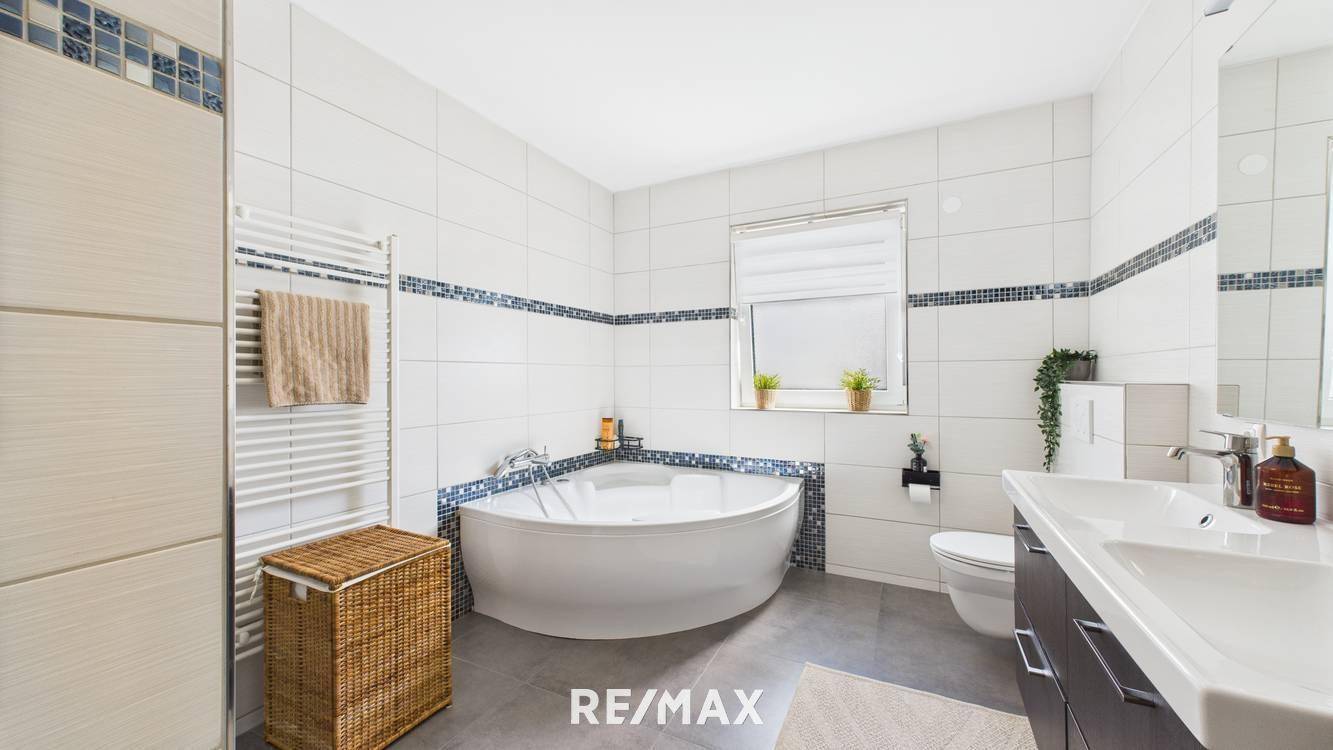 Modernes Badezimmer mit Eckbadewanne, Doppelwaschbecken und beheiztem Handtuchhalter.