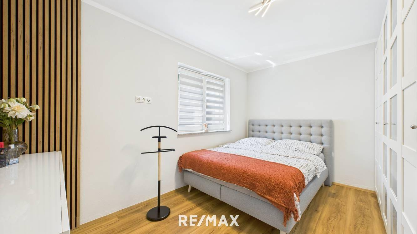Gemütliches Schlafzimmer mit Doppelbett, Holzboden und dekorativer Holzlamellenwand.
