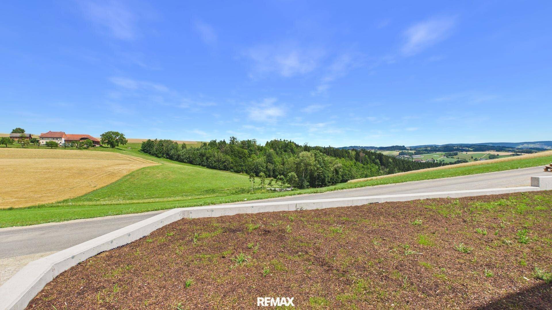 Weitläufiges Grundstück mit Blick auf sanfte Hügel, Felder und Wälder unter klarem Himmel.