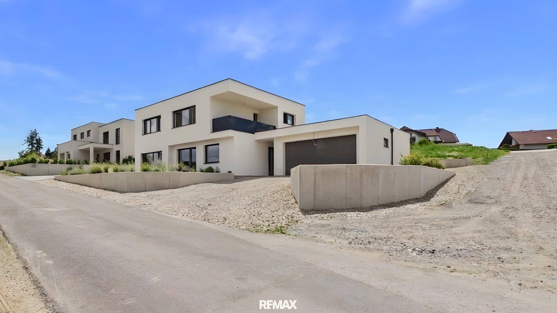 Moderne Architektur eines Neubaus mit klaren Linien, integrierter Garage und weitläufiger Umgebung.