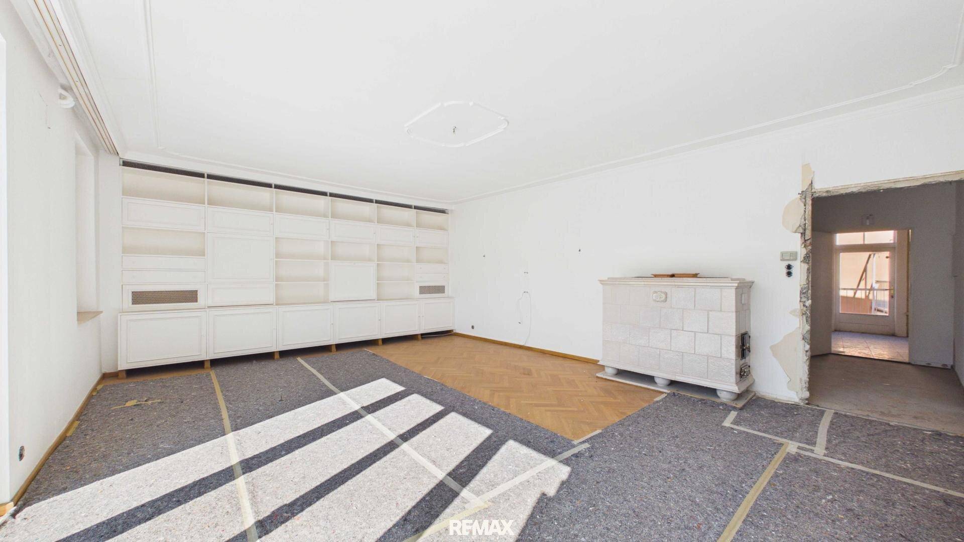 Geräumiges Wohnzimmer mit Kachelofen, Einbauschränken und Parkettboden.