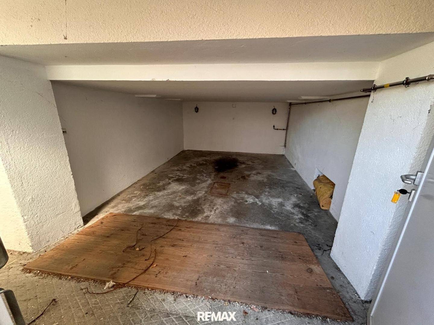 Leere Garage oder Lagerraum mit Betonboden und weißen Wänden.