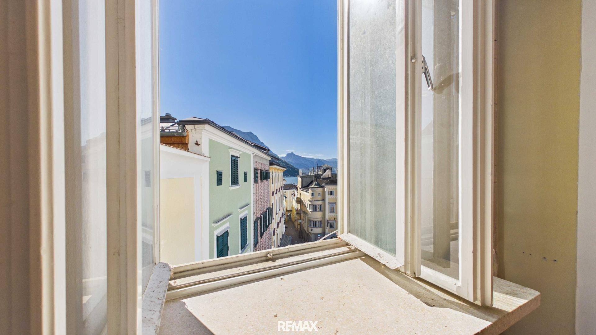 Fensterblick auf die historische Stadt und die umliegende Berglandschaft.