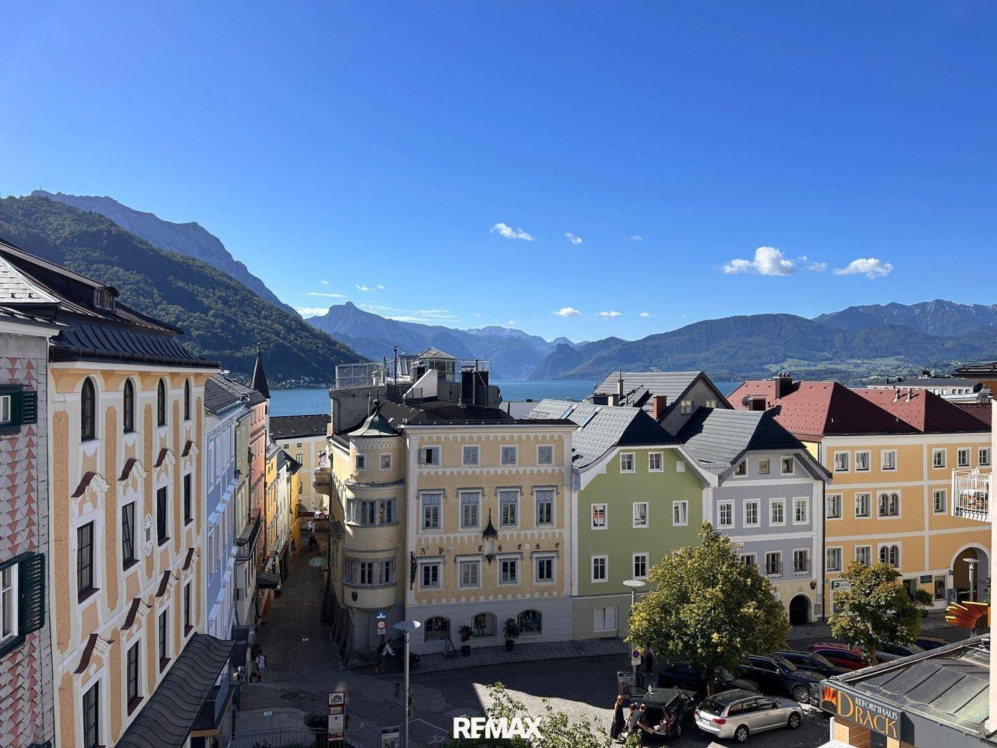 Panoramablick auf die historische Stadt, den See und die Berge unter blauem Himmel.
