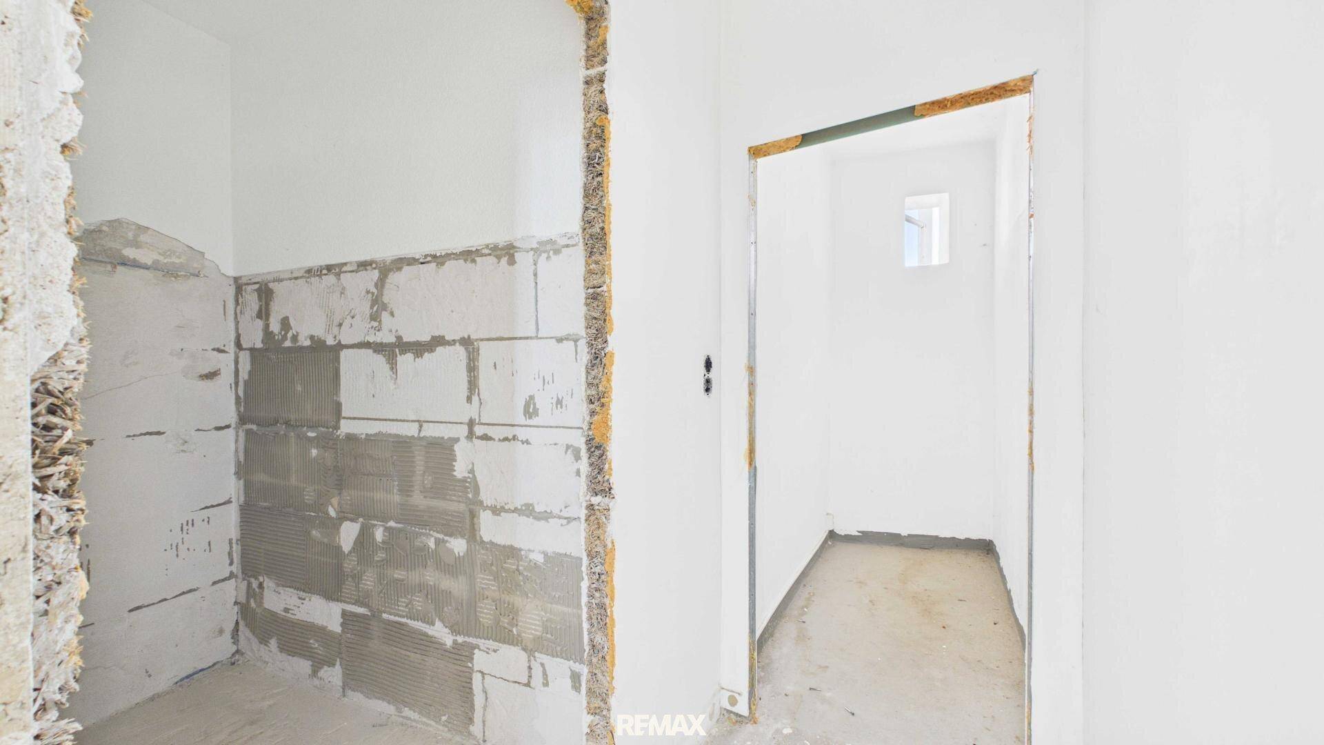Badezimmer in Renovierung mit sichtbaren Wänden und kleinem Fenster.