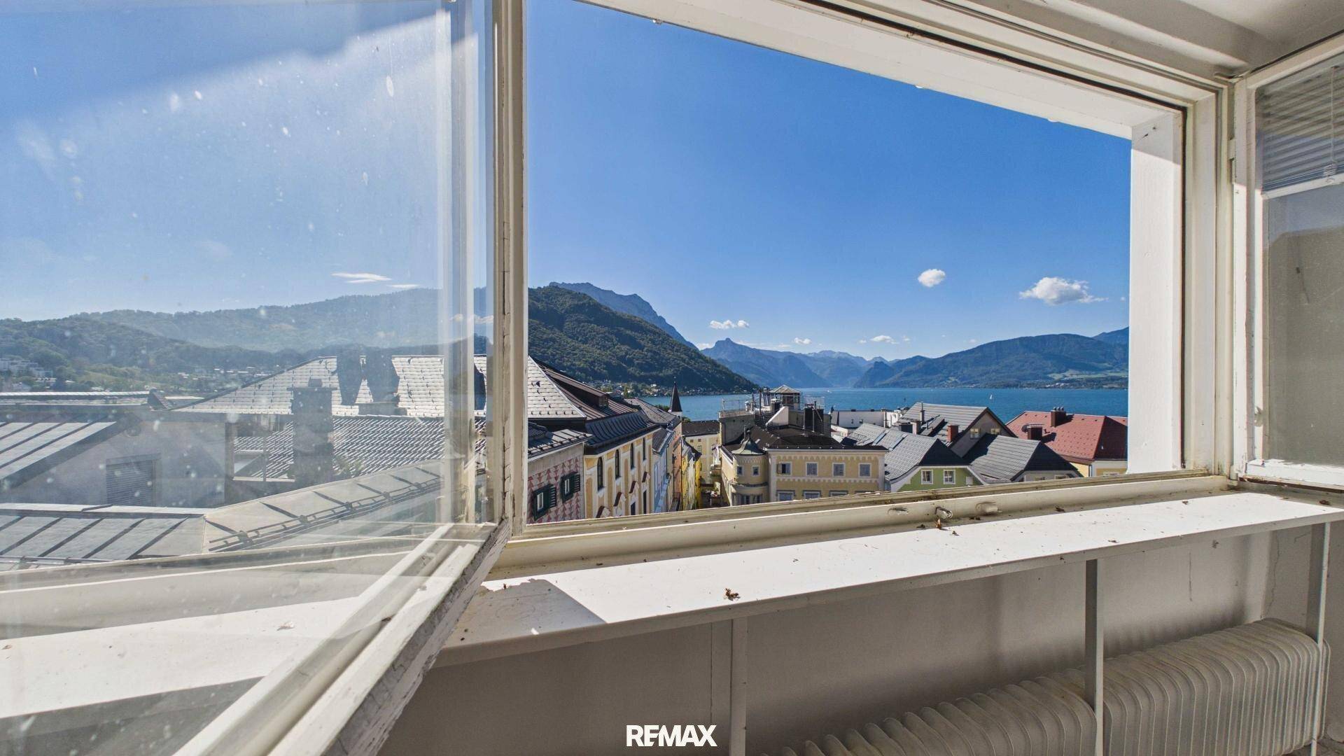 Fensterblick auf die Stadt, den See und die umliegenden Berge.