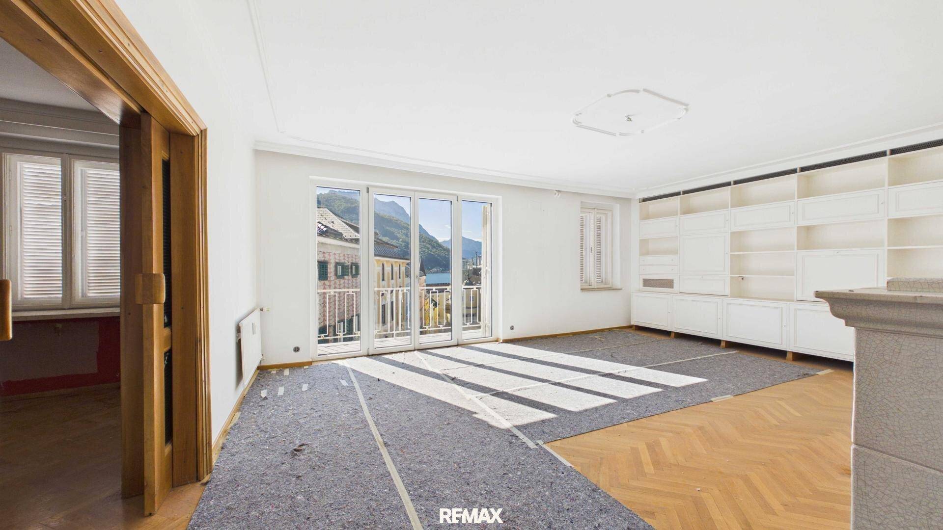 Geräumiges Wohnzimmer mit Parkettboden, Einbauschränken und Balkonzugang.