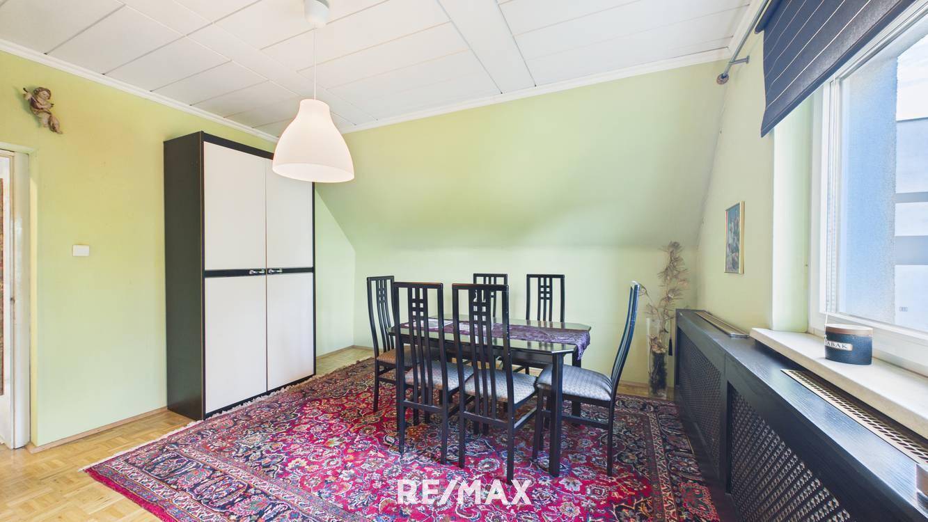 Esszimmer im Dachgeschoss mit Esstisch, Stühlen und Teppichboden.