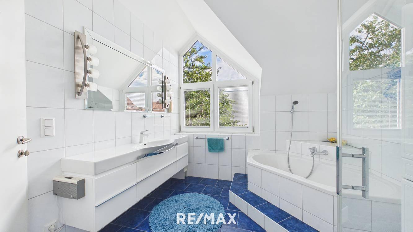 Modernes Badezimmer mit Badewanne, Dusche, Doppelwaschbecken und Dachfenster.