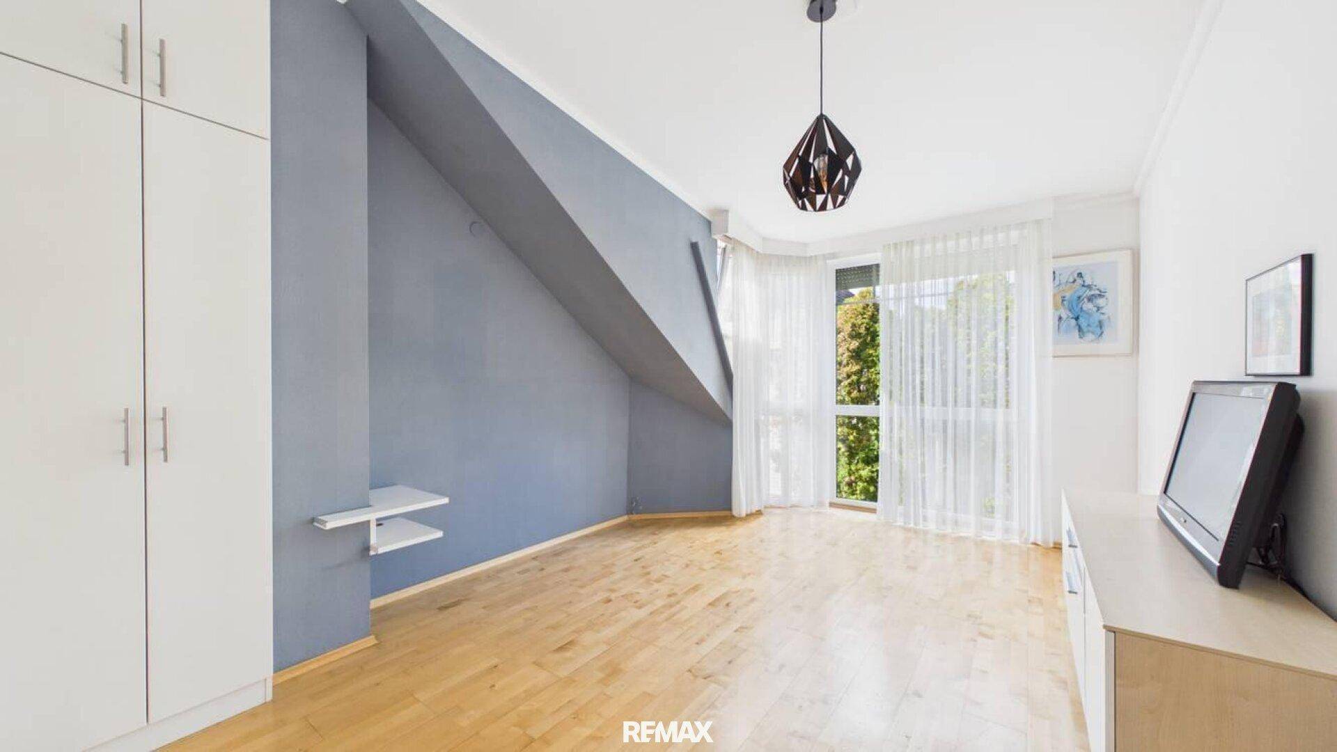 Helles Schlafzimmer mit Dachschräge, Parkettboden und Einbauschrank.