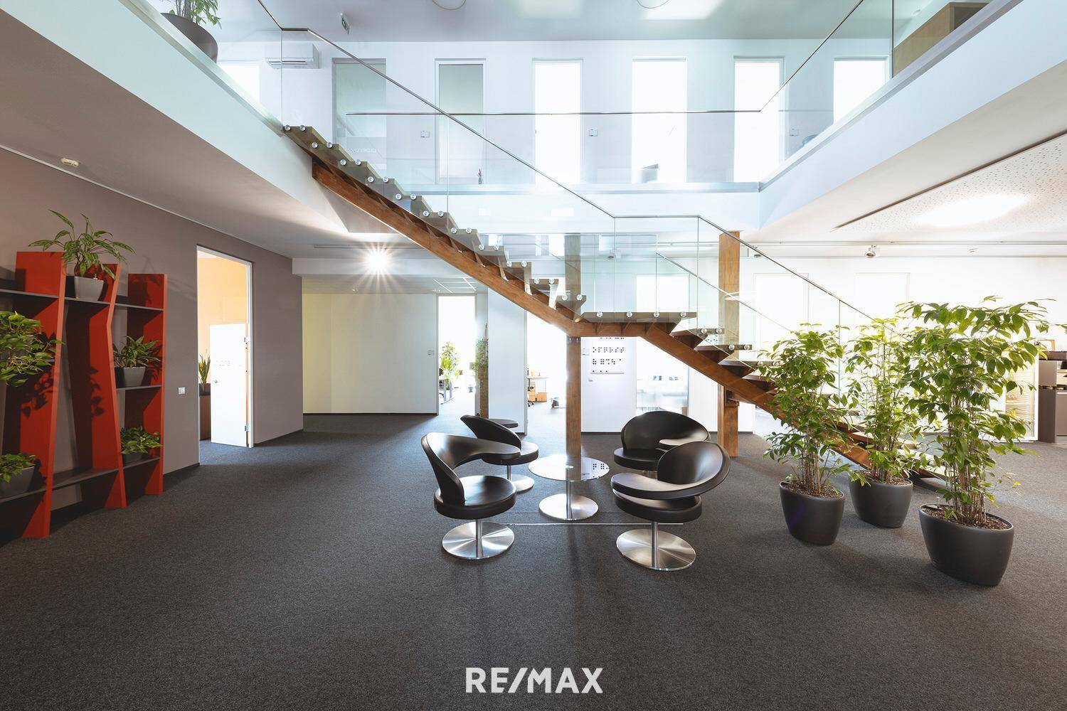 Gemütlicher Loungebereich mit modernen Sesseln, Holzboden und offener Treppe.
