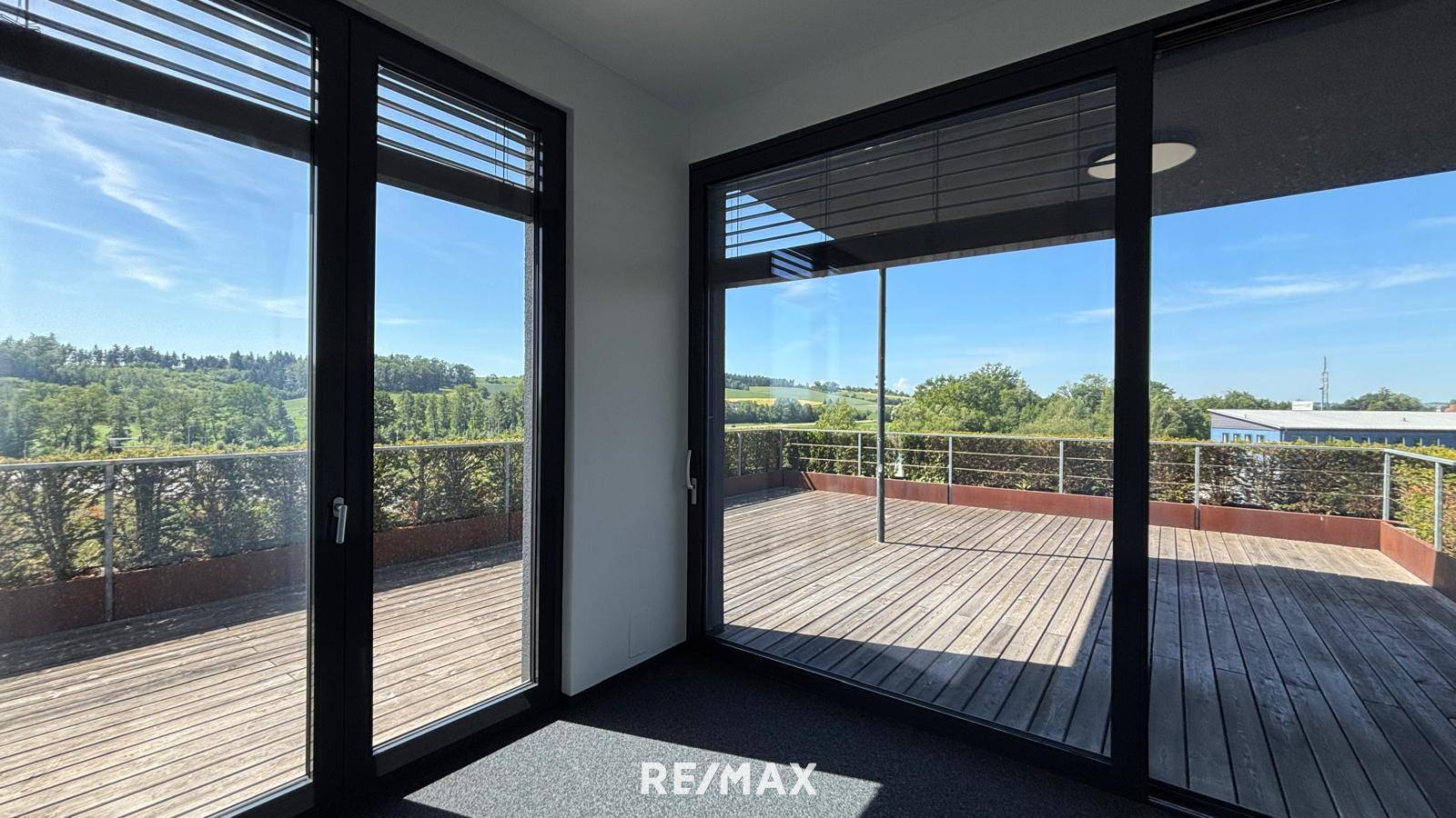 Helles Büro mit großen Fenstern, Zugang zur Terrasse und weitem Blick ins Grüne.