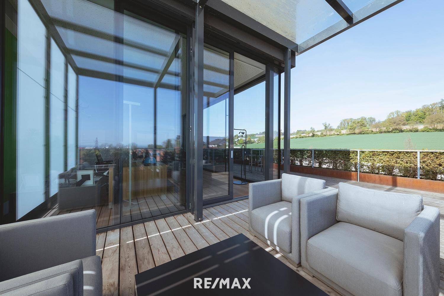 Geräumige Terrasse mit Holzdeck, modernen Loungemöbeln und Blick ins Grüne.