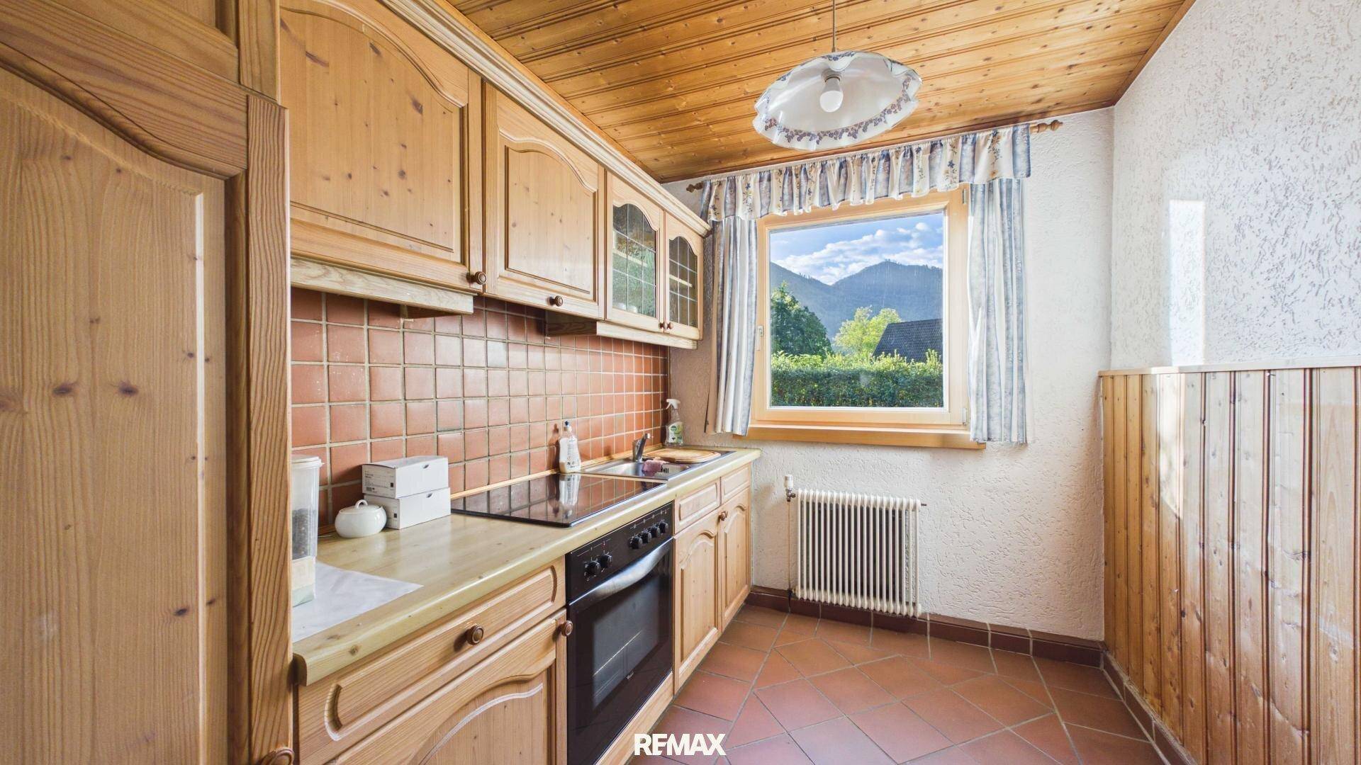 Traditionelle Holzküche mit Fliesenboden, Einbaugeräten und Bergblick.