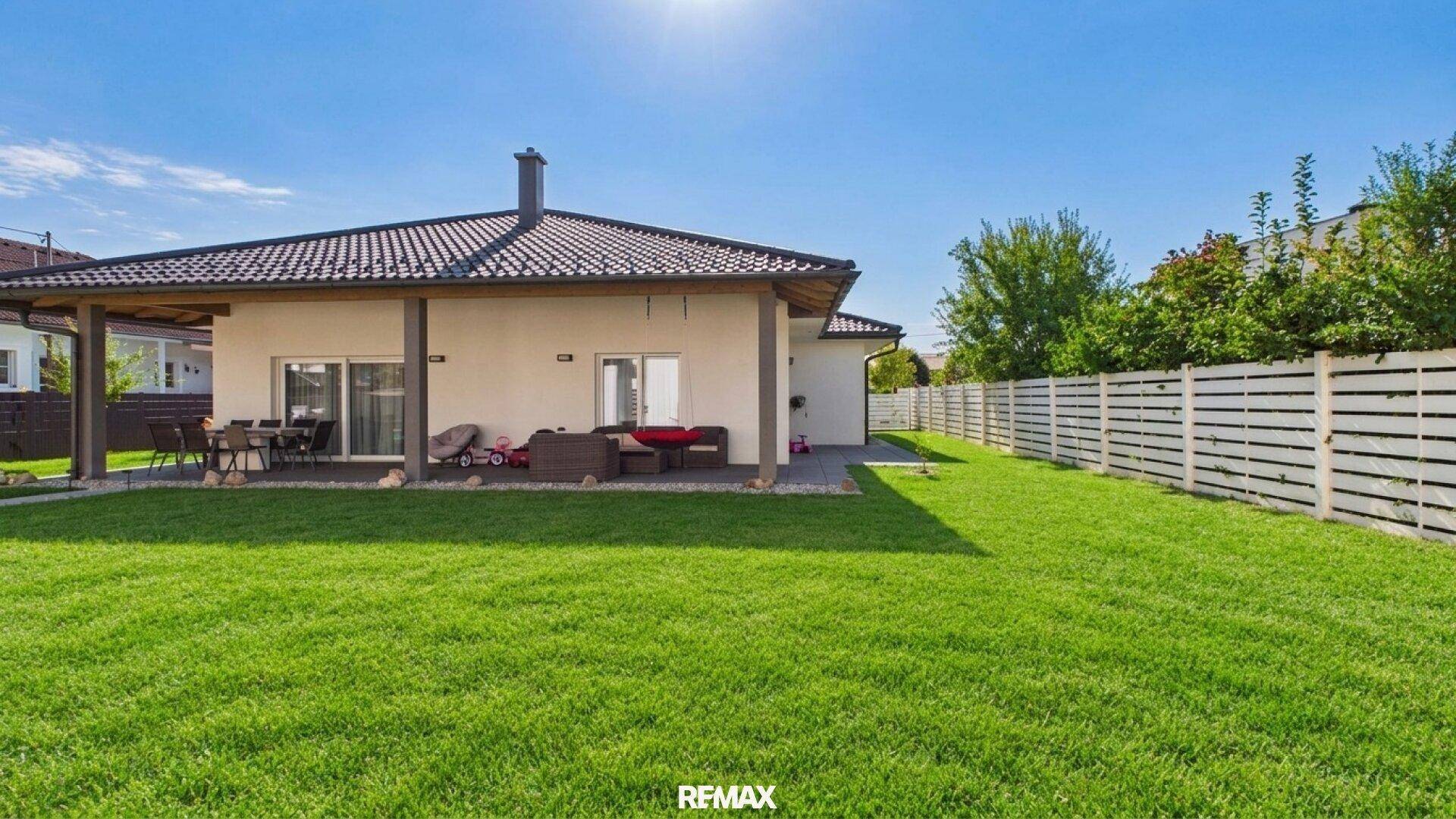 Weitläufiger grüner Garten mit Rasenfläche und überdachtem Terrassenbereich.