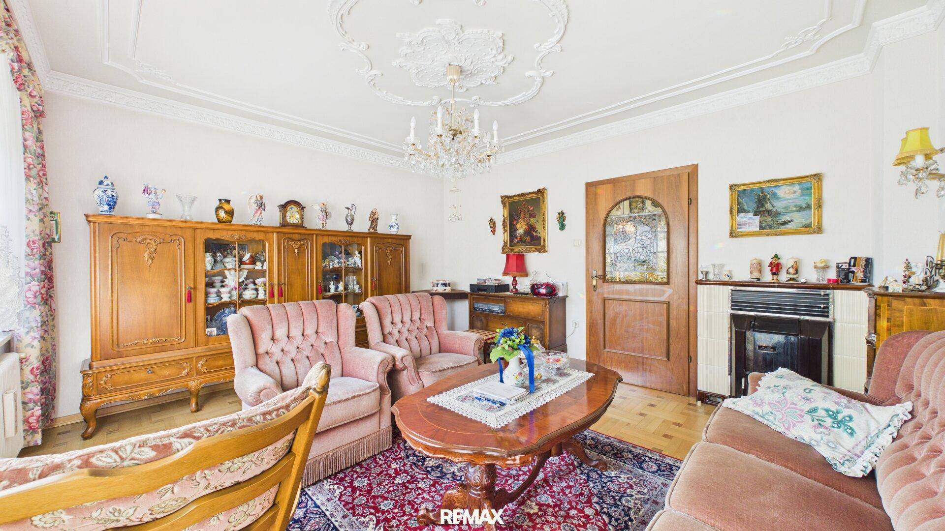 Klassisches Wohnzimmer mit Kamin, Stuckdecke und antiken Möbeln, strahlt Gemütlichkeit aus.