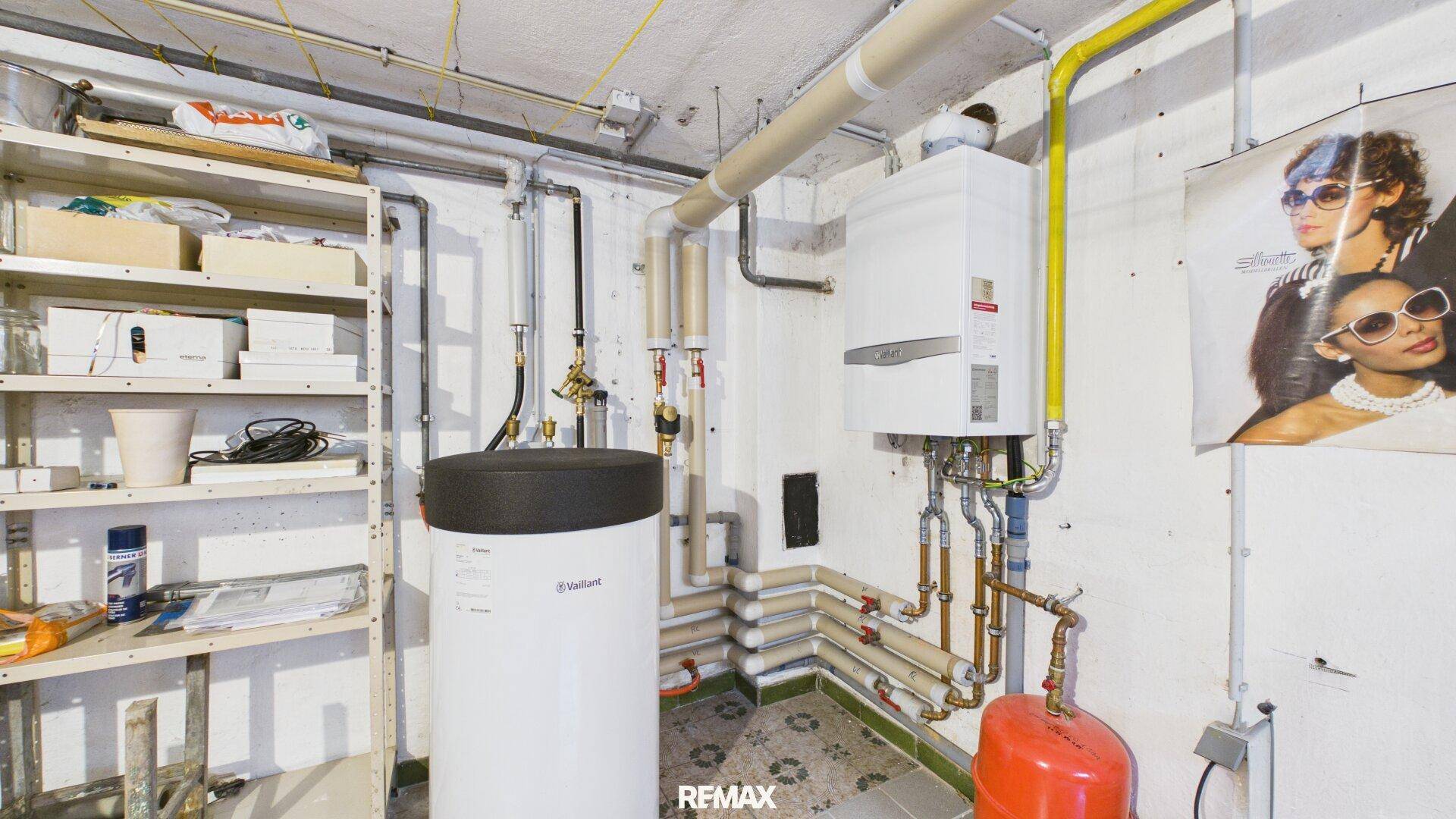 Heizungsraum mit Boiler, Rohren und Lagerregalen, der die technische Ausstattung des Hauses zeigt.