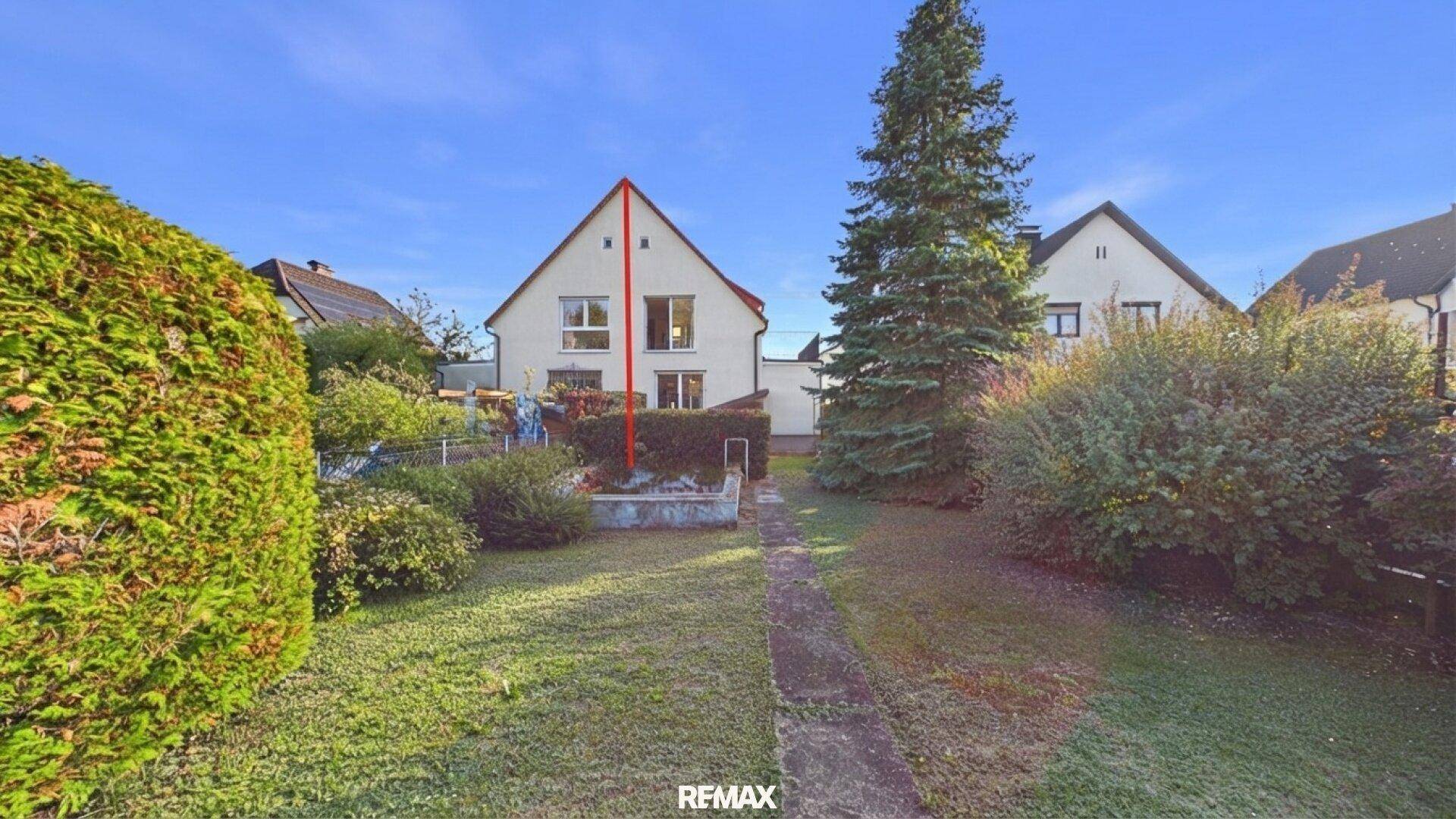Rückansicht des Hauses vom weitläufigen Garten aus, umgeben von viel Grün.