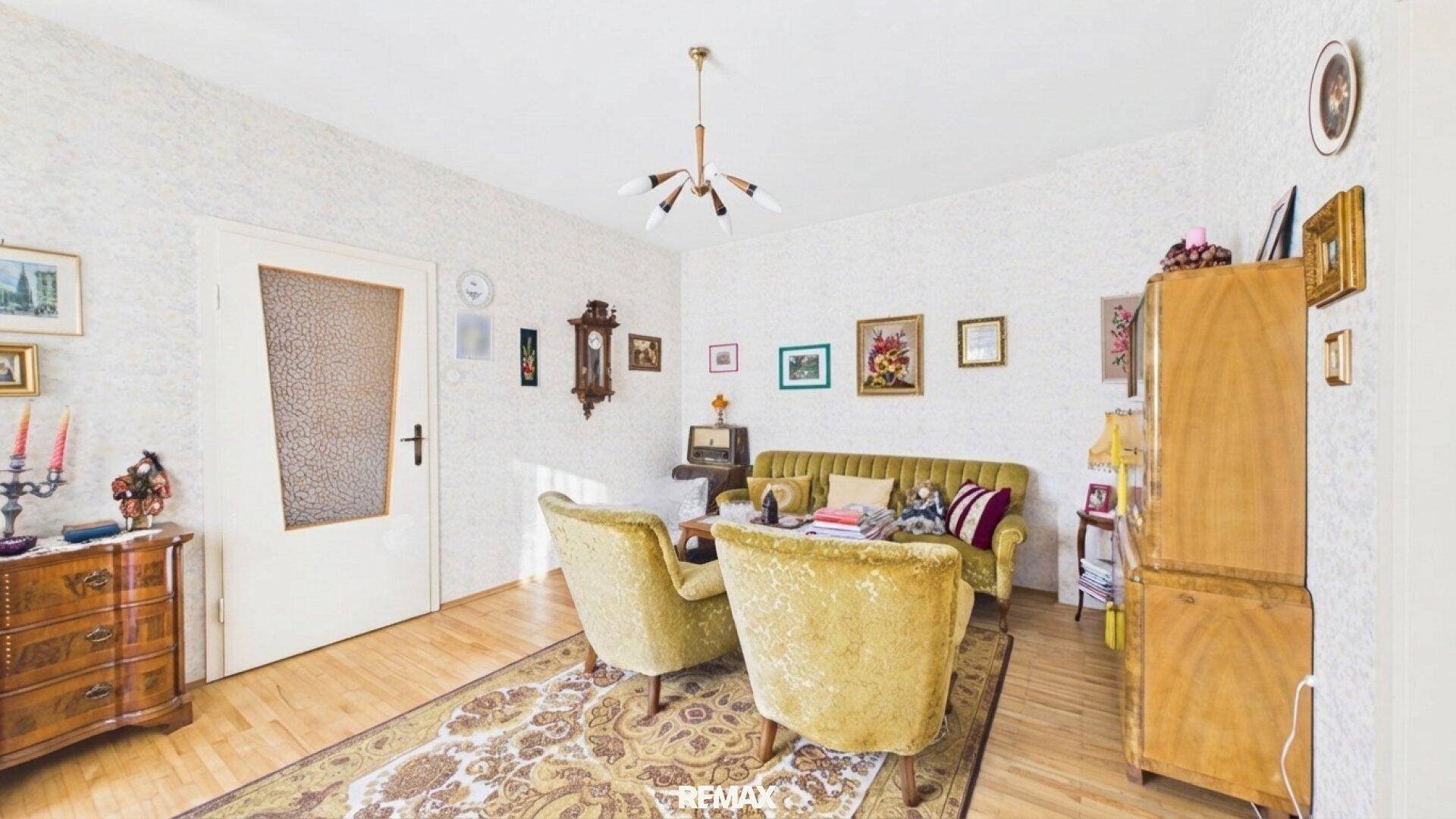Wohnzimmer im Vintage-Stil mit bequemen Sesseln, Holzmöbeln und vielen Bildern an der Wand.