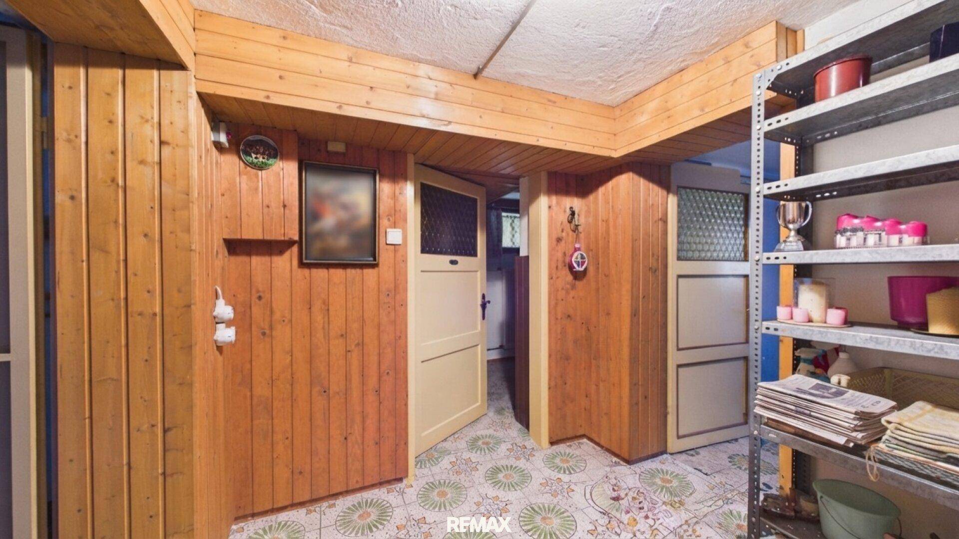 Kellerflur mit Holzvertäfelung, gemustertem Fliesenboden und Regalen für Stauraum.