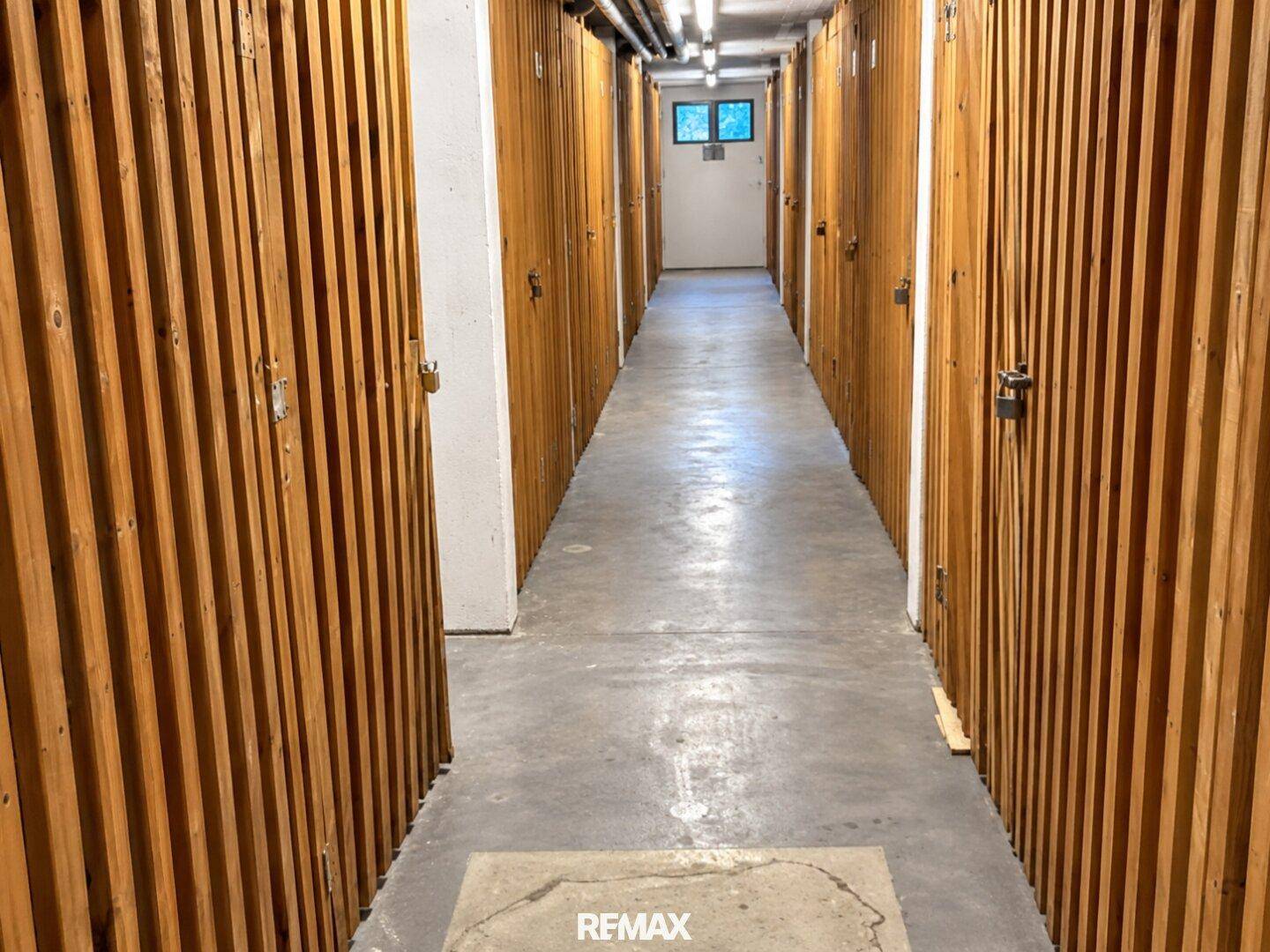 Langer Kellergang mit zahlreichen Holzabteilen, bietet viel Stauraum für die Bewohner.
