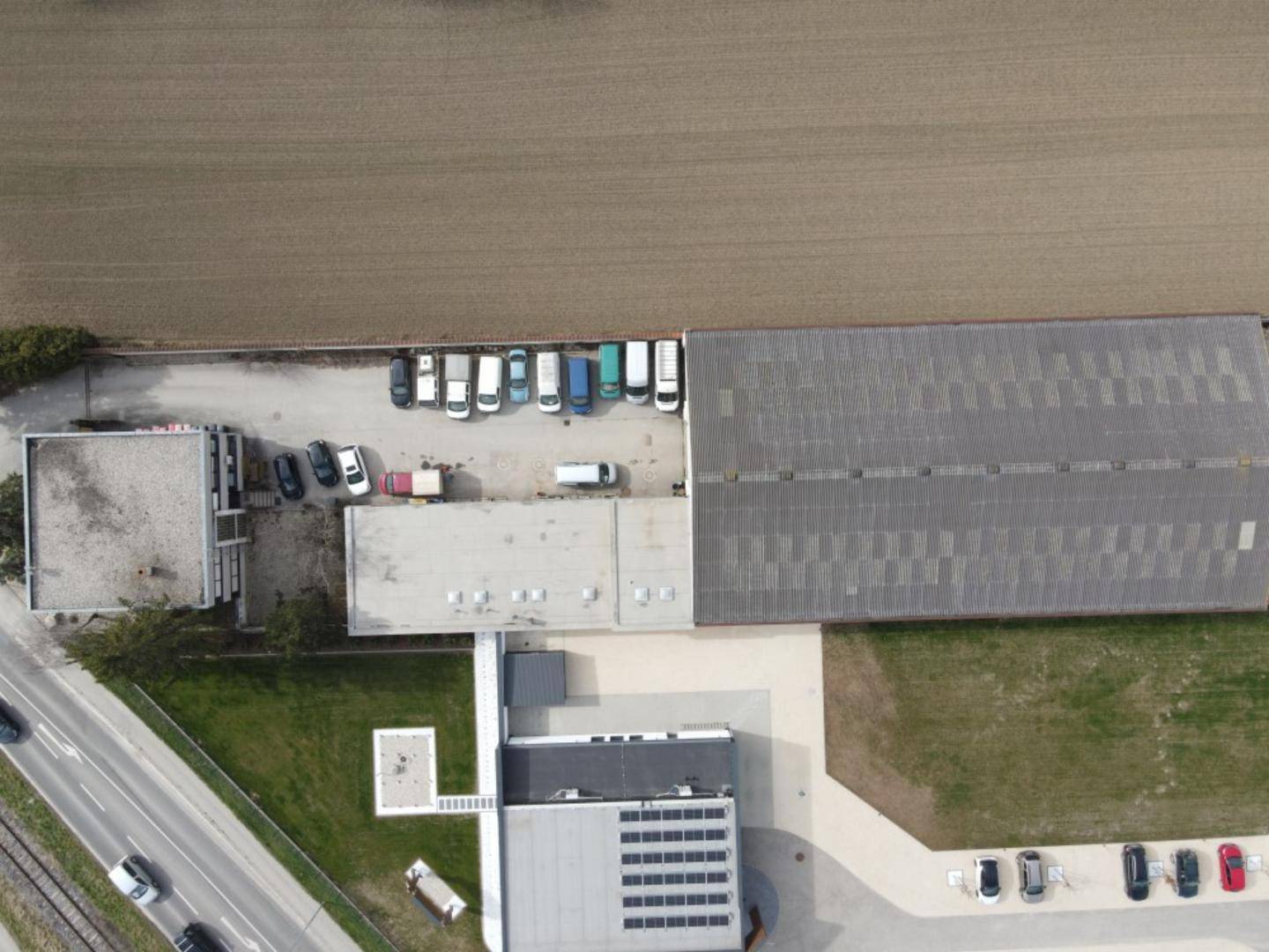 Übersicht aus der Vogelperspektive des Betriebsgeländes mit Zufahrtsstraße und umliegender Landschaft.