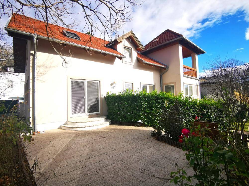 Seitliche Terrasse mit Steinplatten und Hecke, ideal für entspannte Stunden im Freien.
