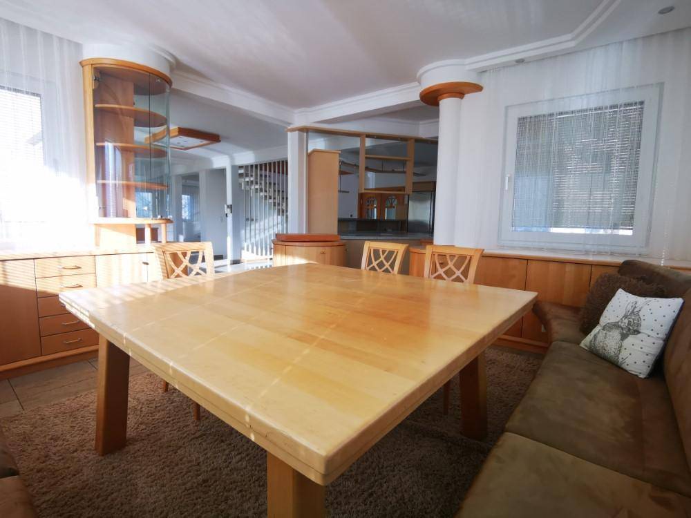 Heller Essbereich mit Holztisch und Vitrine, offen zum Wohnbereich und Treppenhaus.