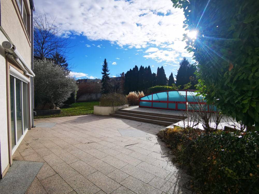 Geräumige Steinterrasse neben dem Haus mit Zugang zum Garten und überdachtem Poolbereich.