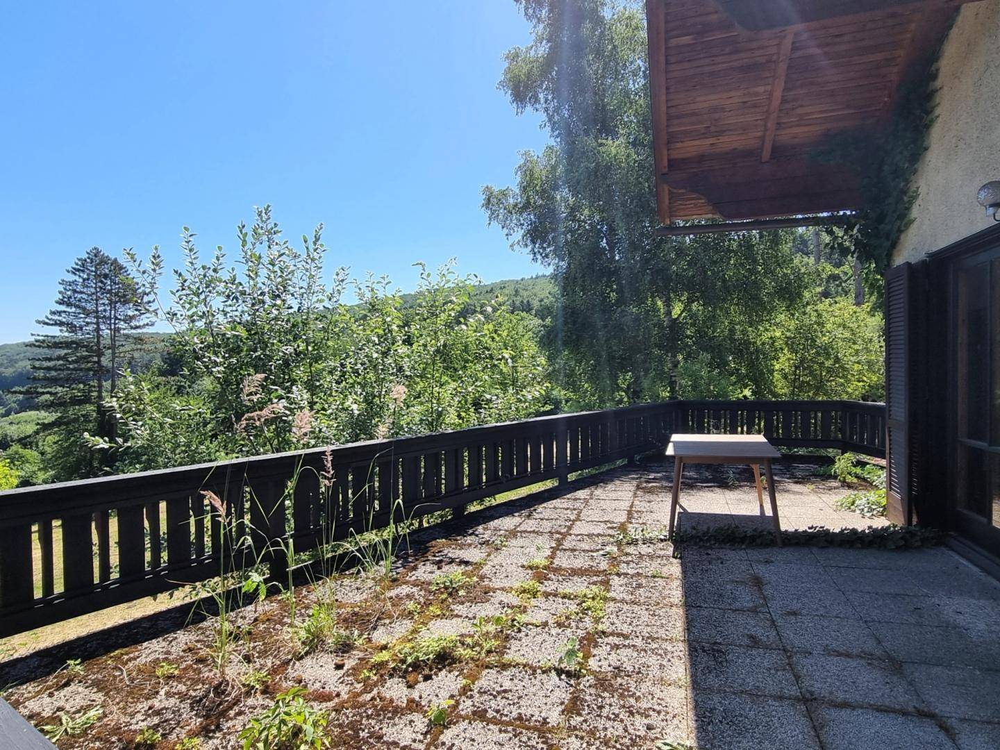 Großer Balkon mit Holzgeländer und weitem Blick auf die grüne Hügellandschaft.