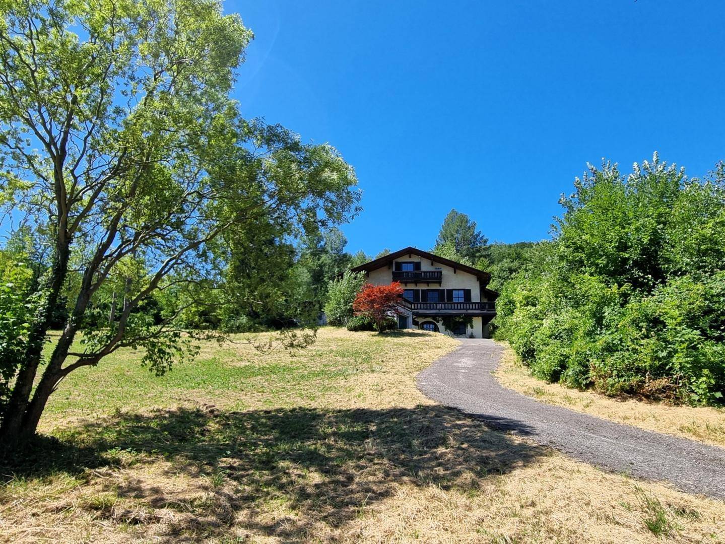 Zufahrt zum traditionellen Landhaus, umgeben von weiten Wiesen und Bäumen.