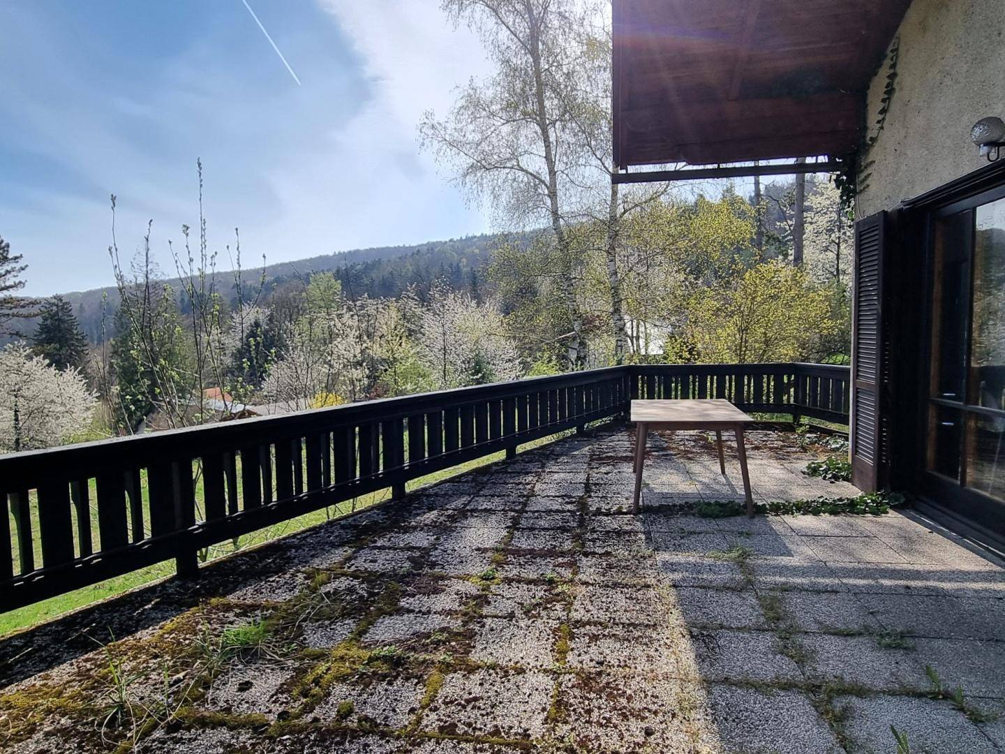 Großer Balkon mit Holzgeländer und weitem Blick auf die blühende Frühlingslandschaft.