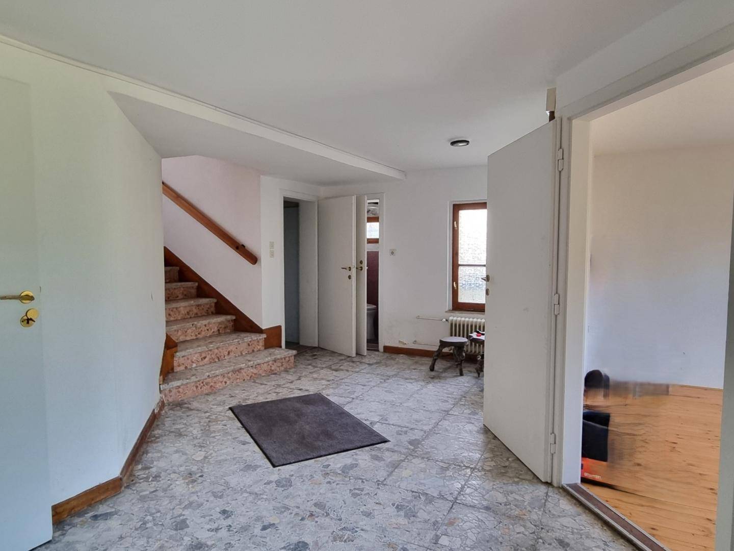 Geräumiger Flur mit Terrazzoboden, Treppe und mehreren Türen zu angrenzenden Räumen.