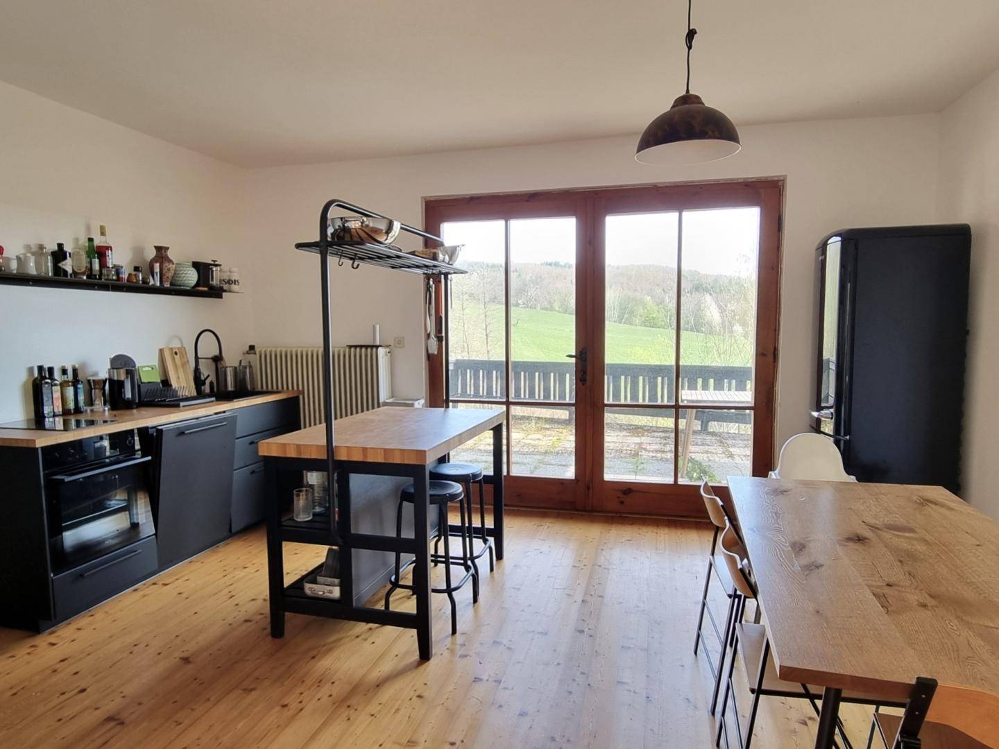 Moderne Küche mit schwarzer Einrichtung, Holztheke und Essbereich, mit Zugang zur Terrasse.